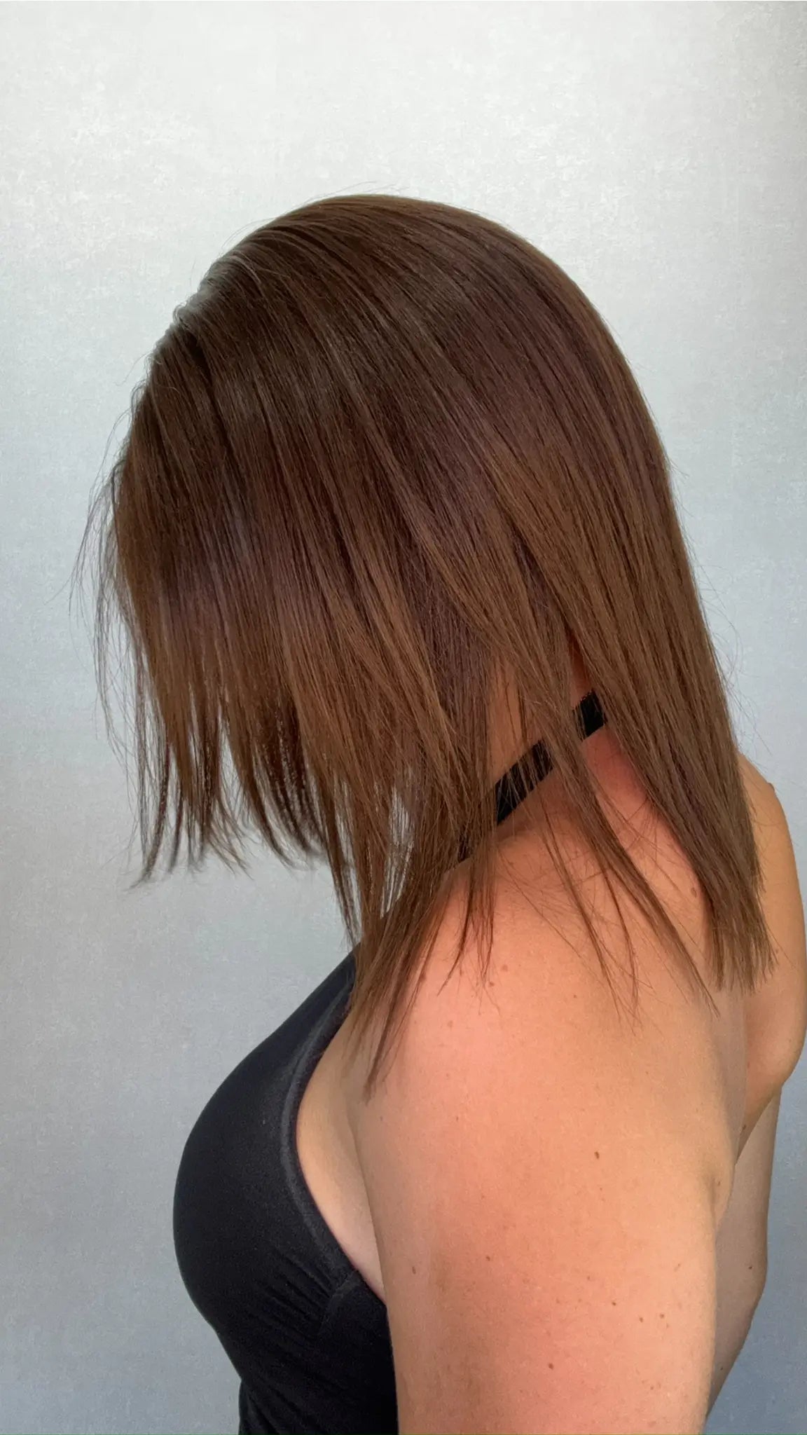 Side view of the APRIL wig, a 12-inch neutral brunette lace front wig with soft, subtle warm highlights and a lightweight feel.