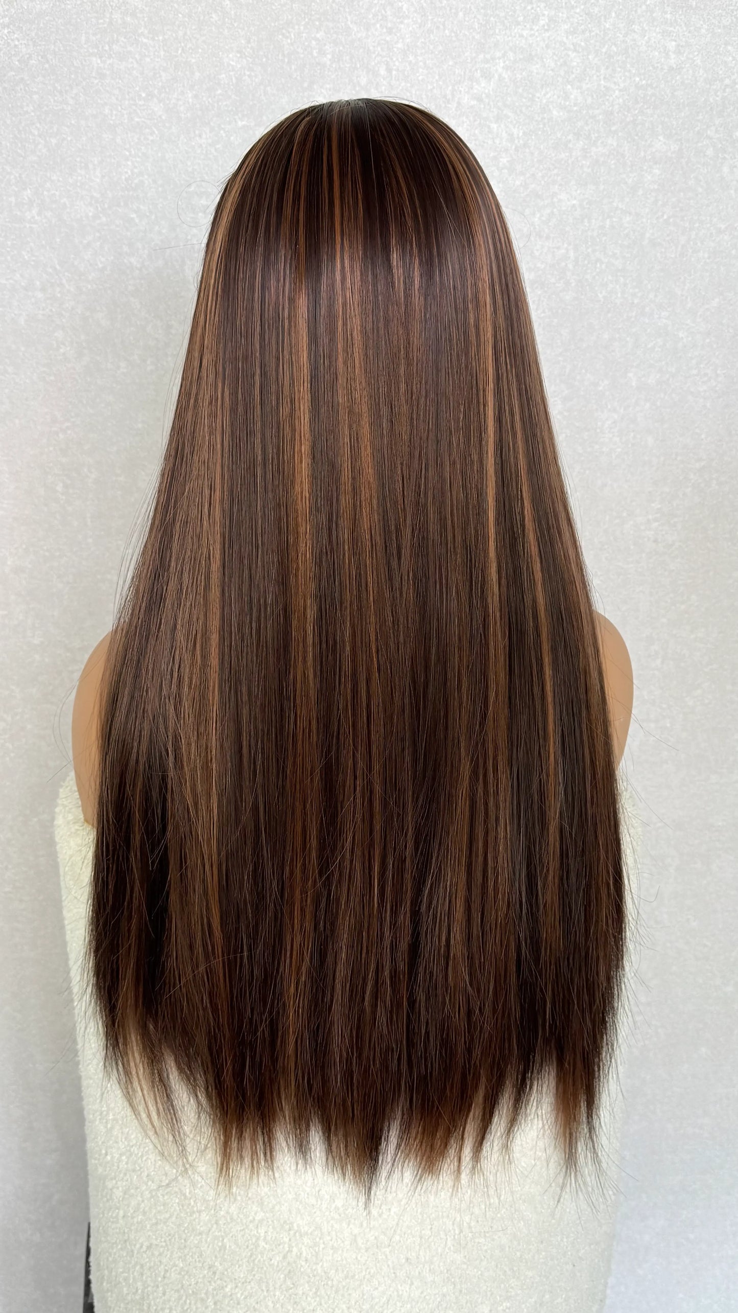 snythetic headband wig from the back showing the highlights in brown hair. natural lighting, long length synthetic hair.