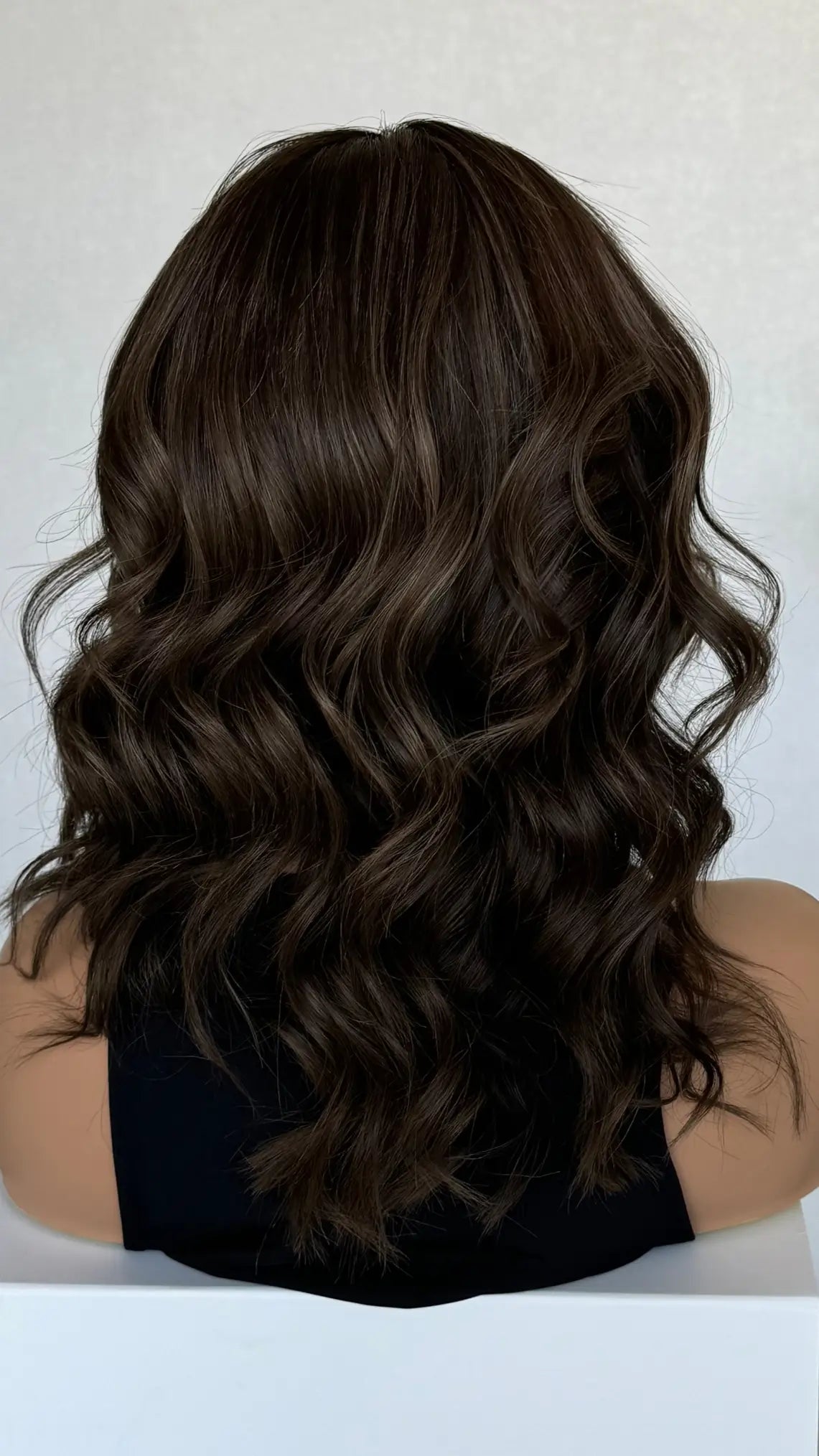 Back view of the Riley wig, showcasing its deep brunette base with subtle cool highlights for added depth and dimension
