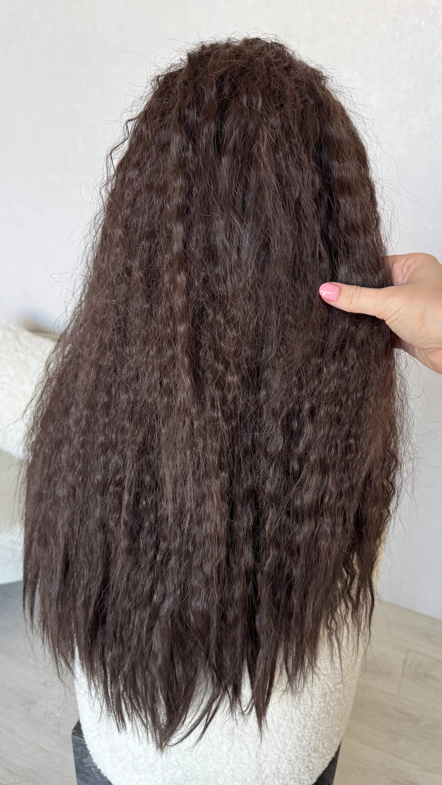 back view holding long dark brown hair curly waves.