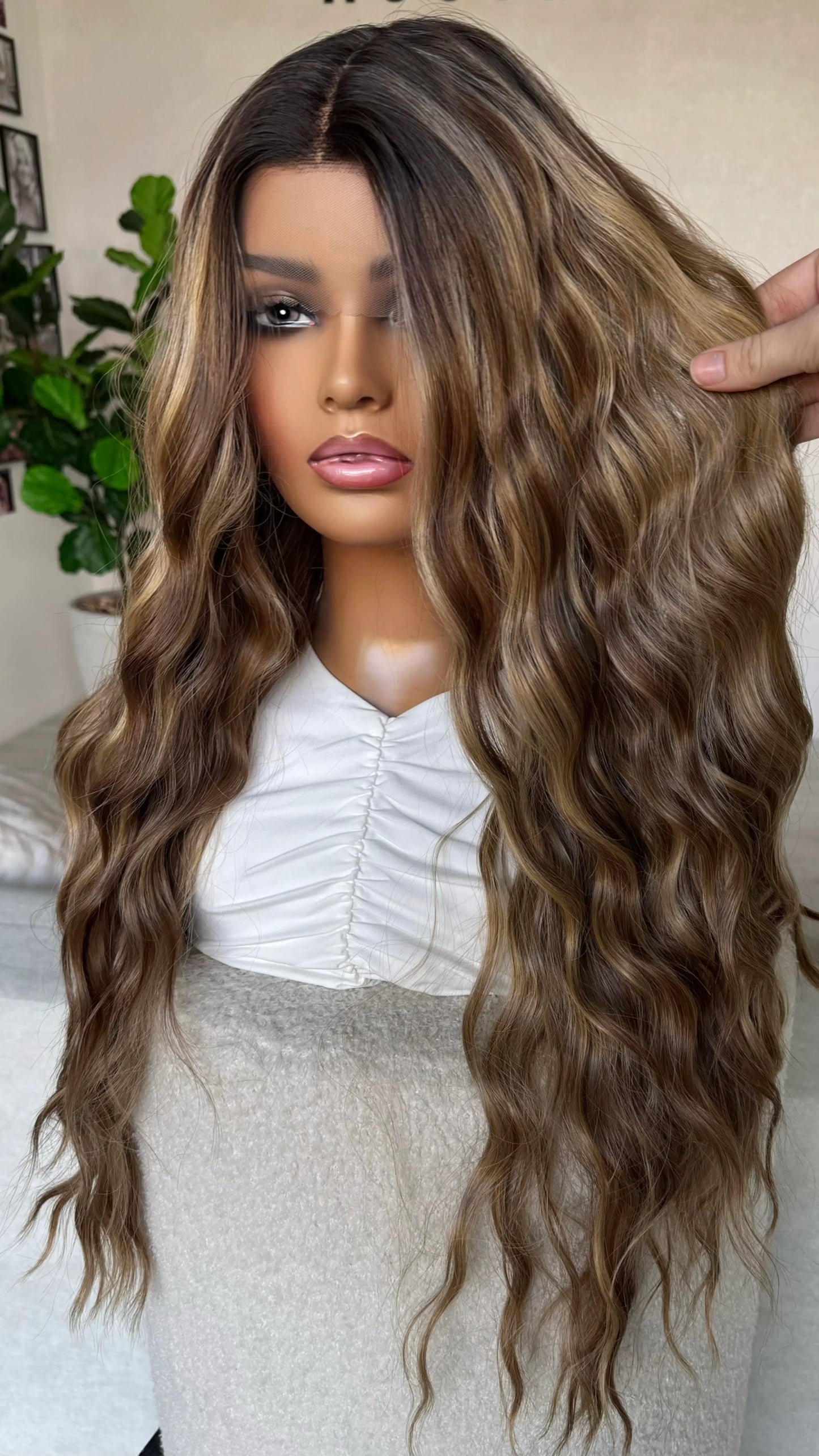 holding brunette hair with caramel light highlights, multi toned brunette synthetic. lacefront, natural wig.