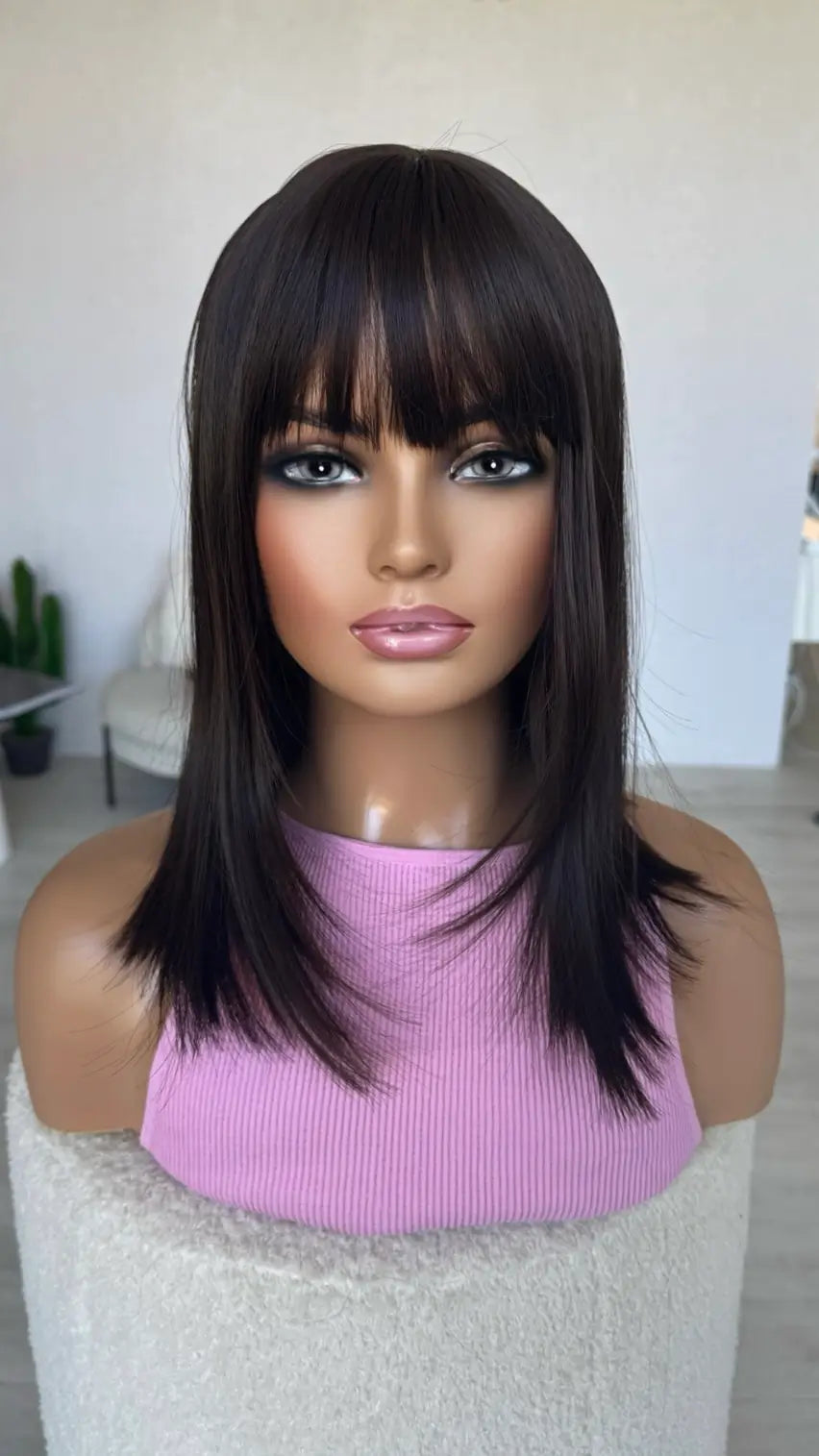 Mannequin head with a black wig and pink top on a white background