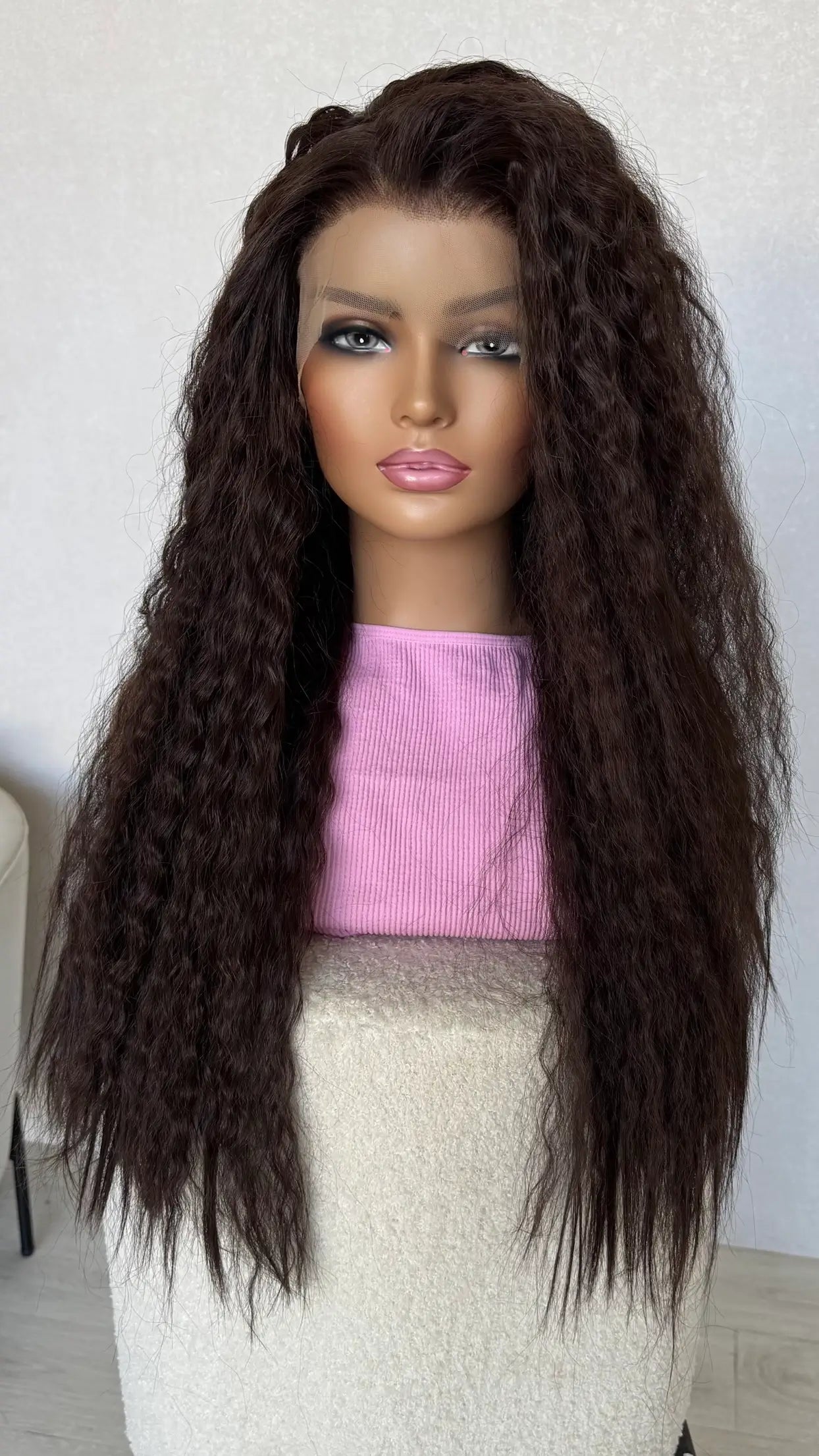 Mannequin head with long brown hair and a pink top on a white background
