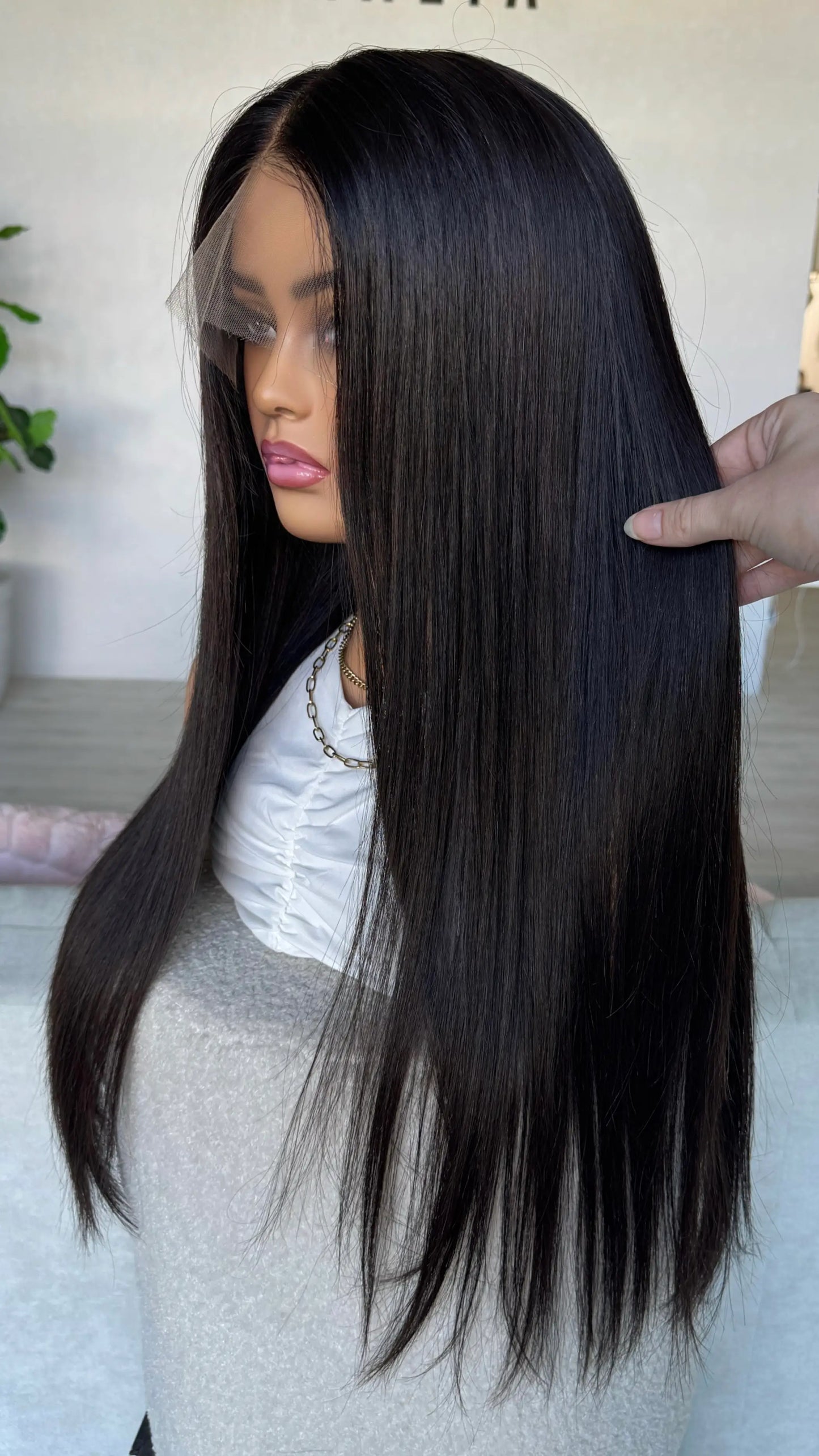 side on view holding the black hair wig. handmade wig in australia, natural hairline.