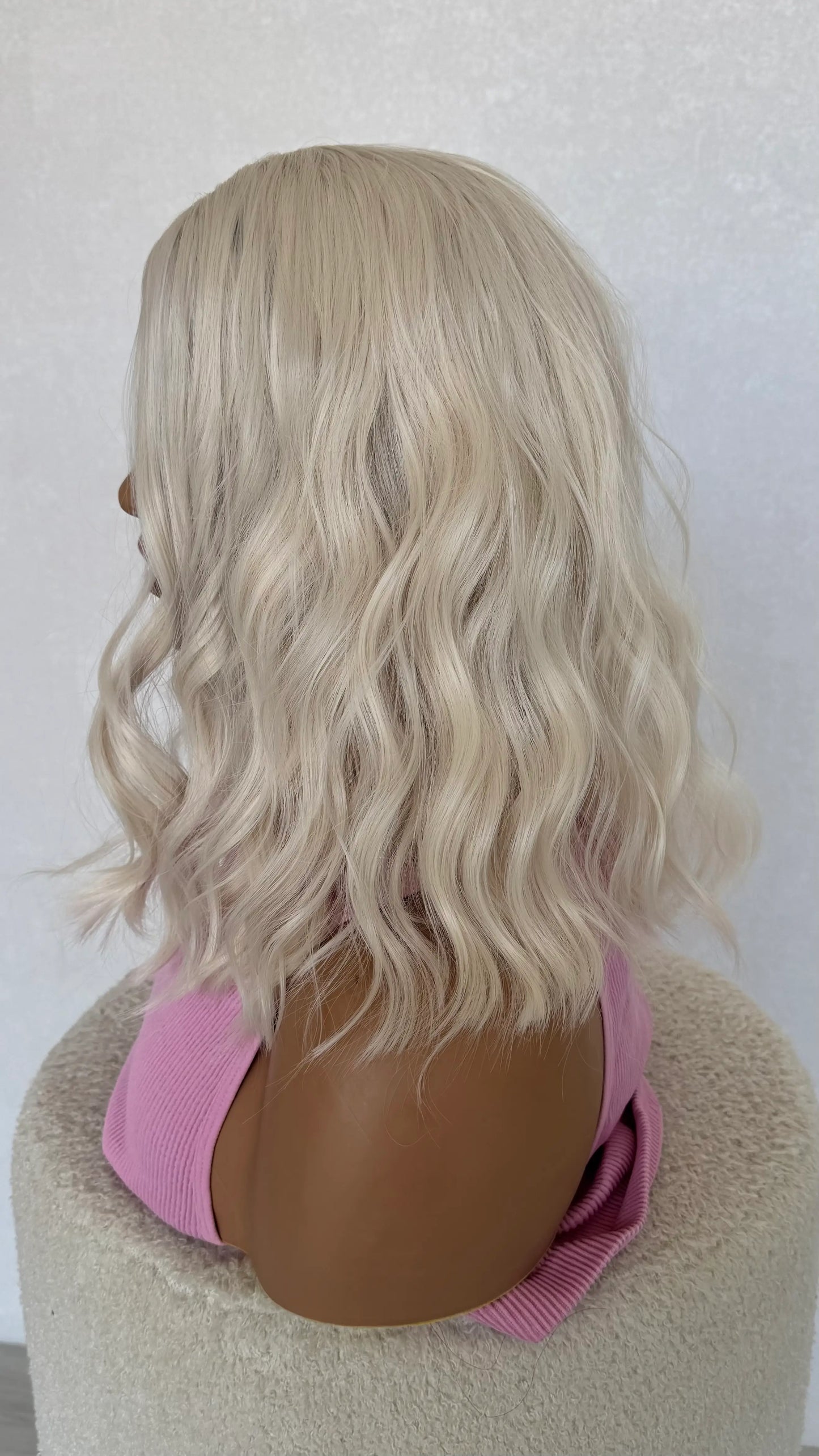 Blonde wig on a mannequin head with a pink top against a white background