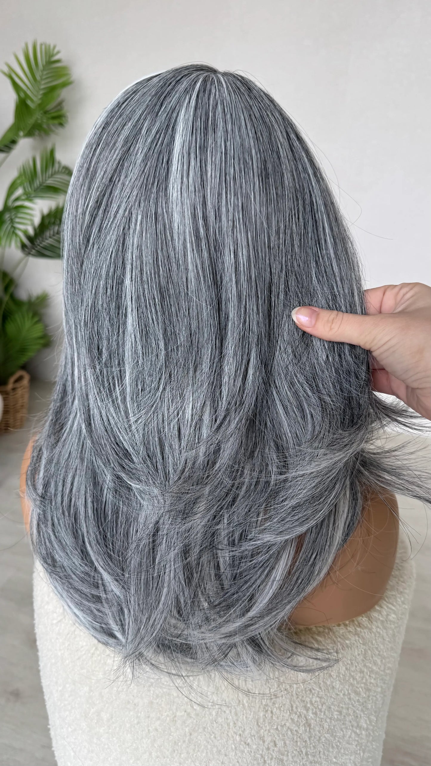 back view holding salt and pepper grey wig hair, heat safe fibers