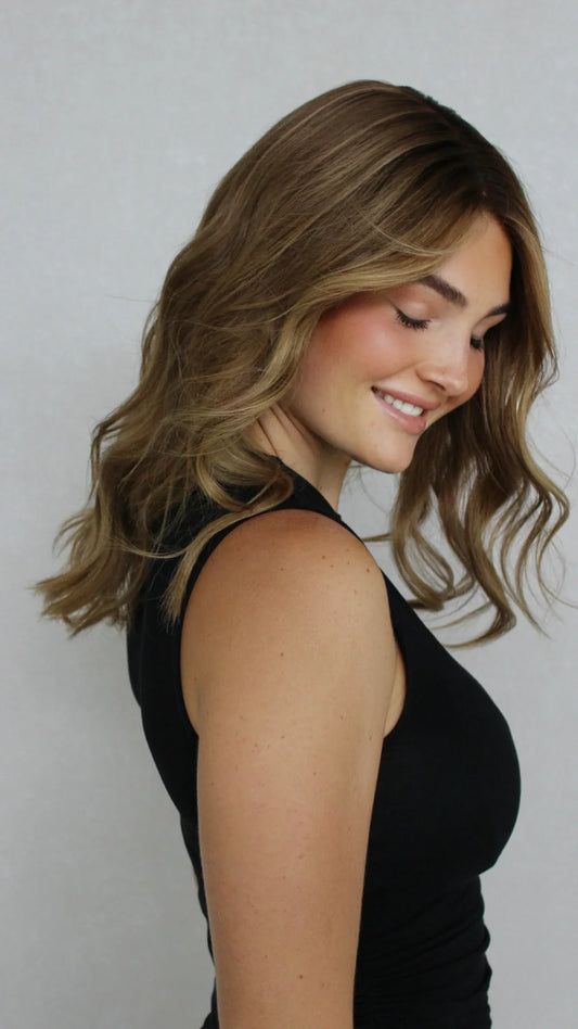 Soft waves cascade down as the model showcases a perfectly styled human hair wig in a professional shoot