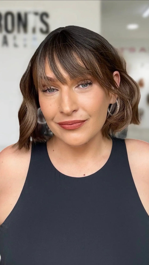 a 10 inch wavy hair short bob with a long fringe and wavy brunette hair with lighter warm brunette ends. Dark roots with middle part.