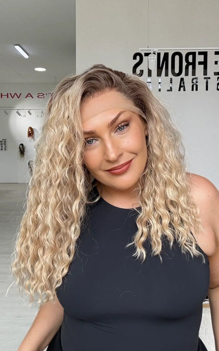 a curly lacefront warm golden blonde hair wig with a soft brunette shadow root, mid chest length hair with light layers for movement.