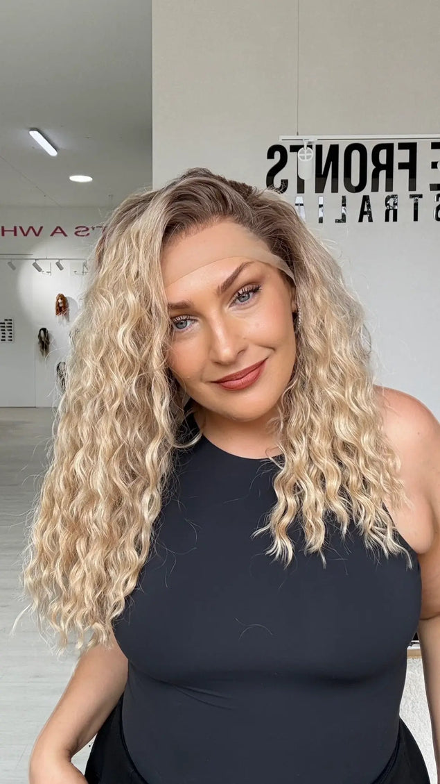 a curly lacefront warm golden blonde hair wig with a soft brunette shadow root, mid chest length hair with light layers for movement.