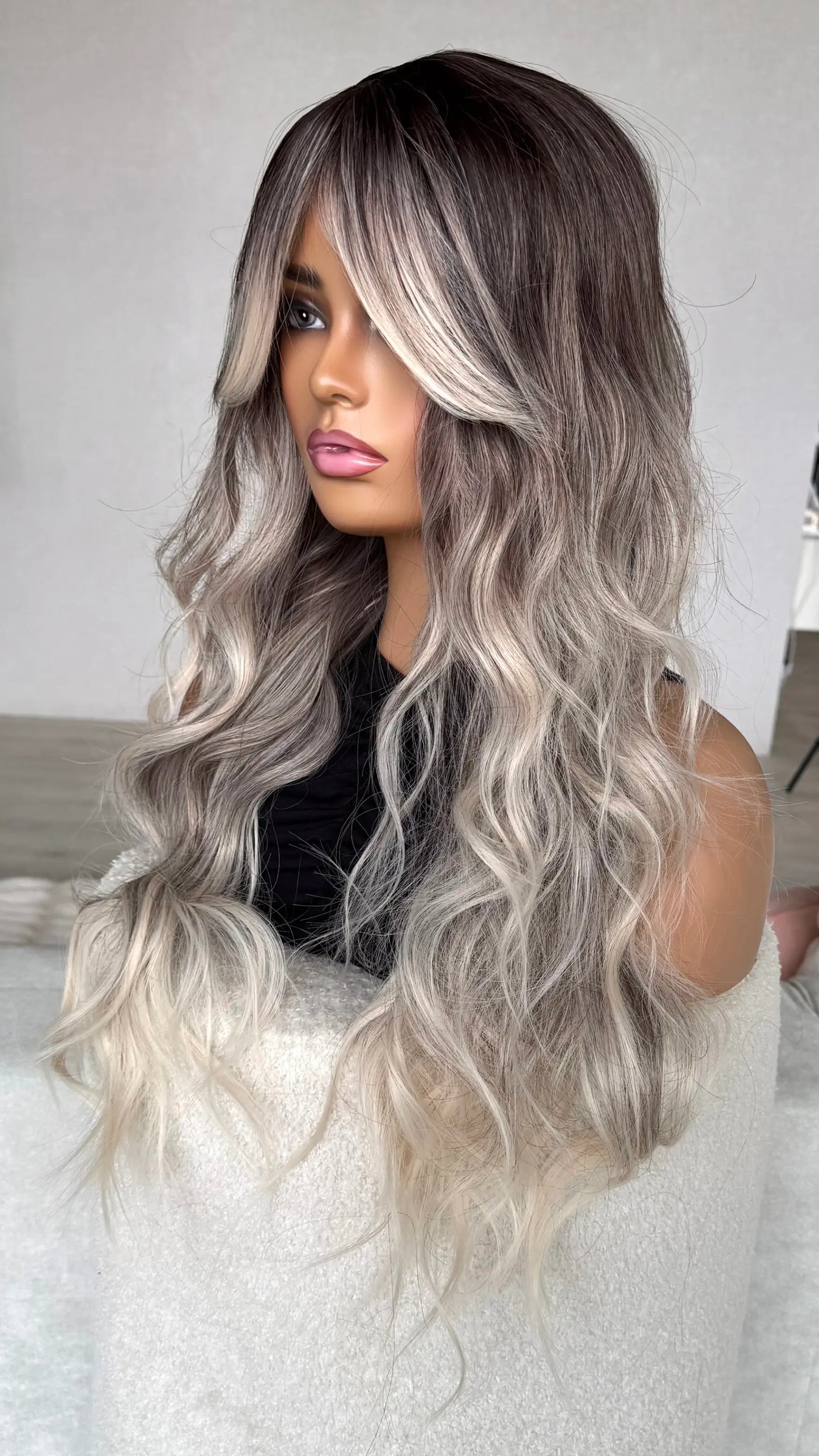 side on view of dark root to silver blonde hair, wavy hair. heat safe synthetics.