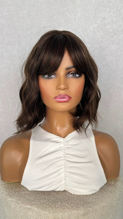 Heat- Friendly Synhthetic wig with a fringe from the front view. wavy with the fringe parted to the side.