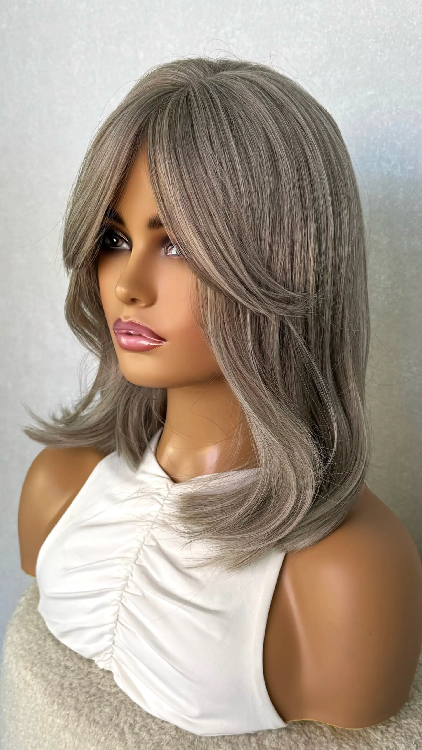 grey silver hair synthetic wig from the side on. showing curtain bangs and multi tones of grey. natural grey wig.