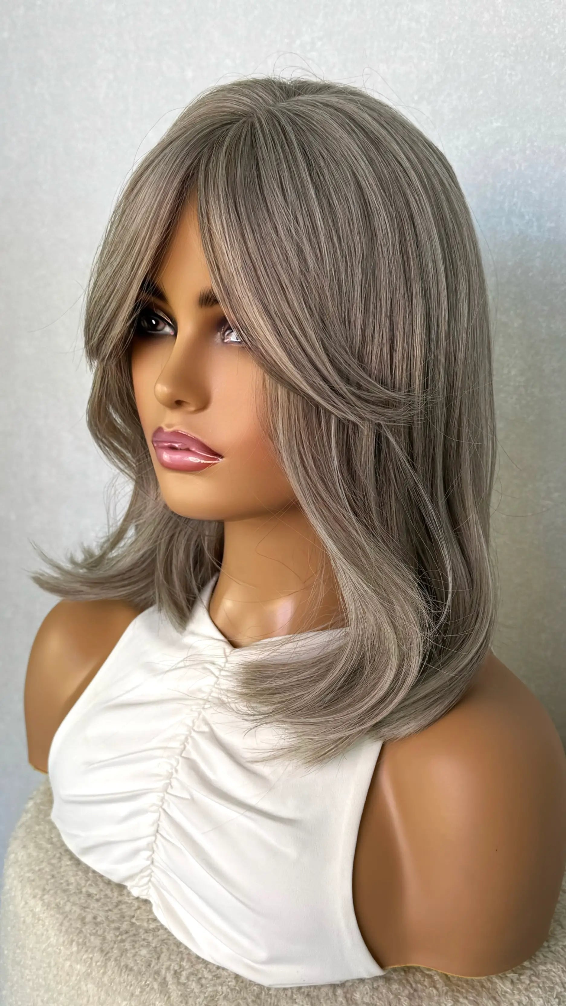 grey silver hair synthetic wig from the side on. showing curtain bangs and multi tones of grey. natural grey wig.