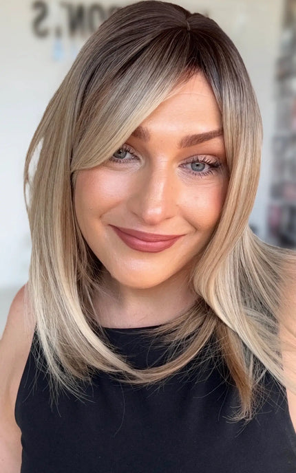 a multi toned blonde bob with light layers and curtain bangs for shaping around the face. darker shadow root to blonde ends.