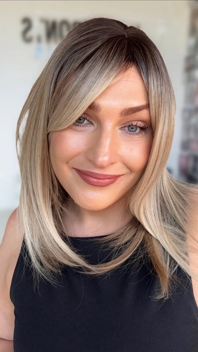 a multi toned blonde bob with light layers and curtain bangs for shaping around the face. darker shadow root to blonde ends.