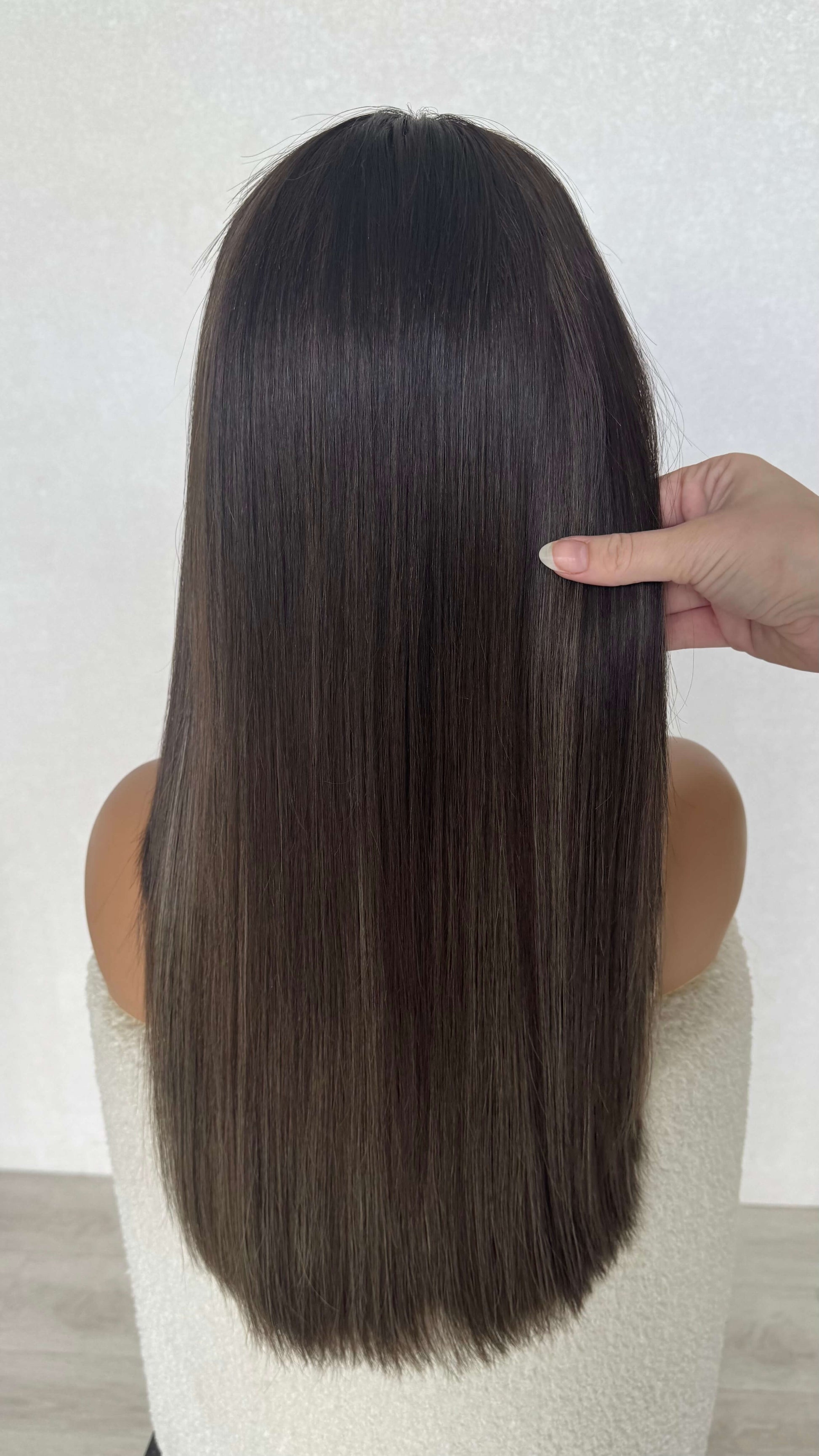 holding long brunette hair, cool toned with highlights, handmade wig australia.