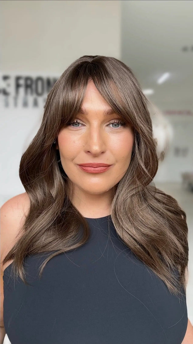 ash brunette layered hair with middle part and long curtain bangs. layers around the face for shaping.