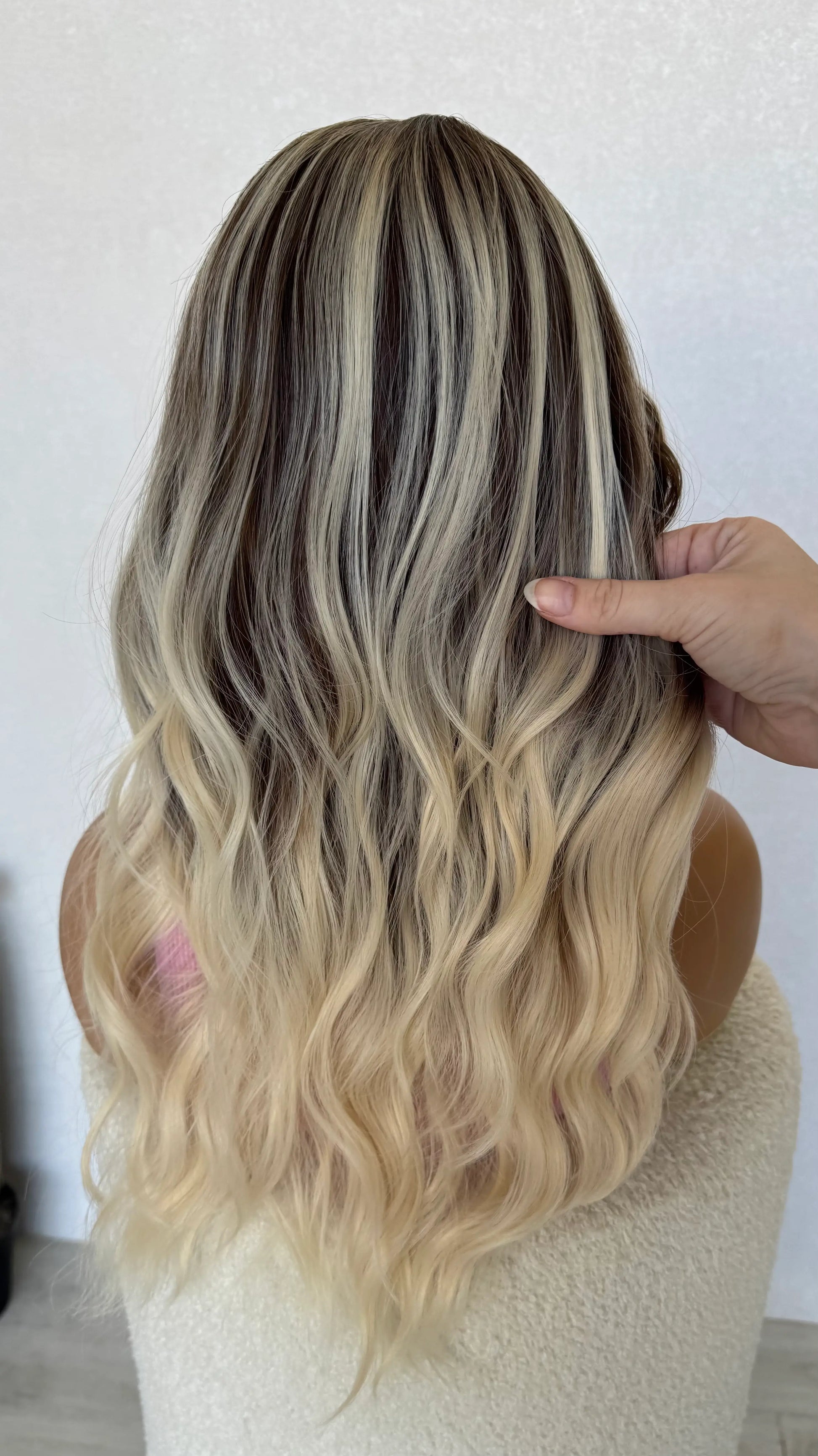 back view holding hair, ash brunette with platinum highlights throughout.