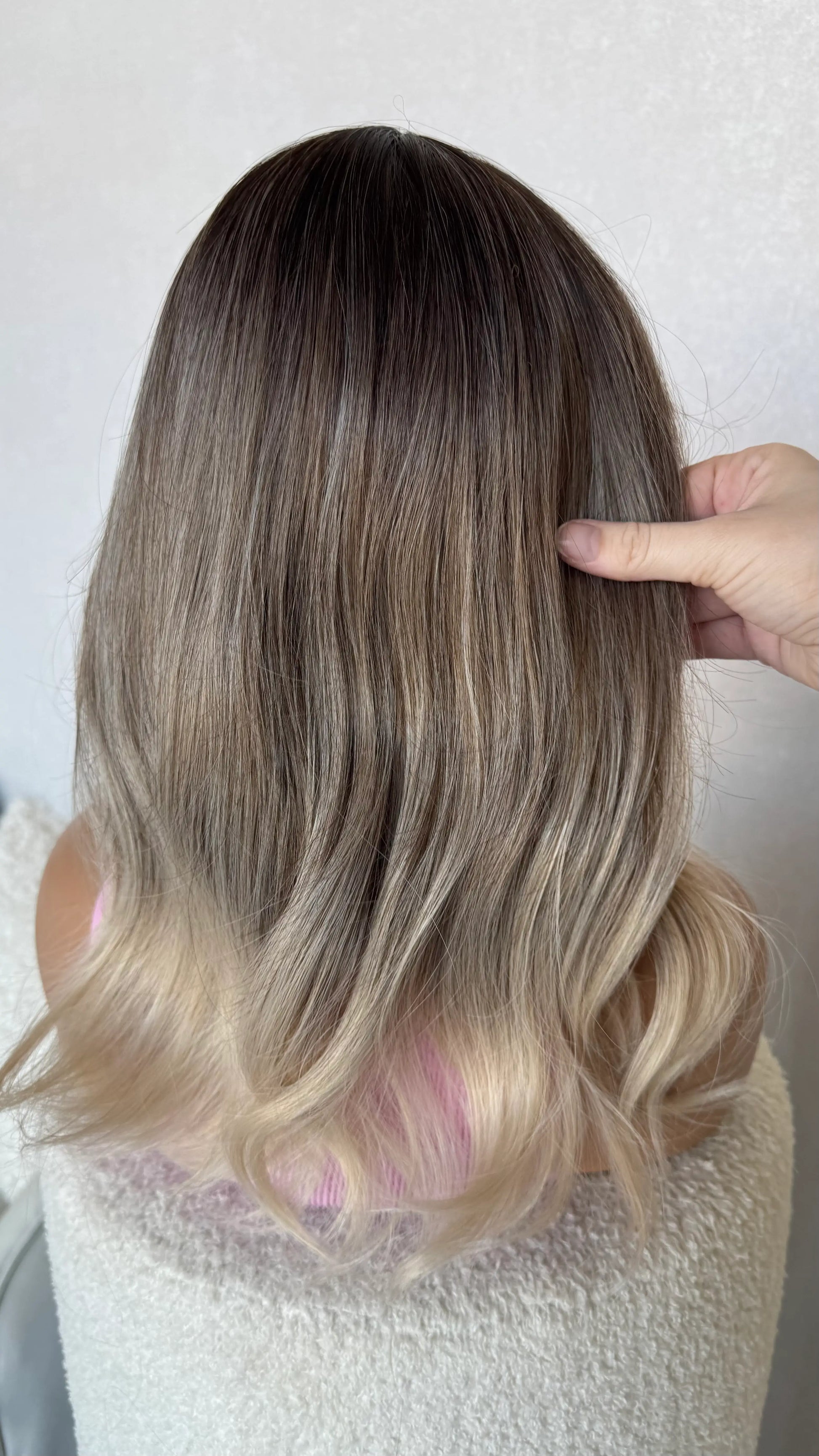 back view holding hair dark root to platinum blonde ends, glueless fringe synthetic wig.