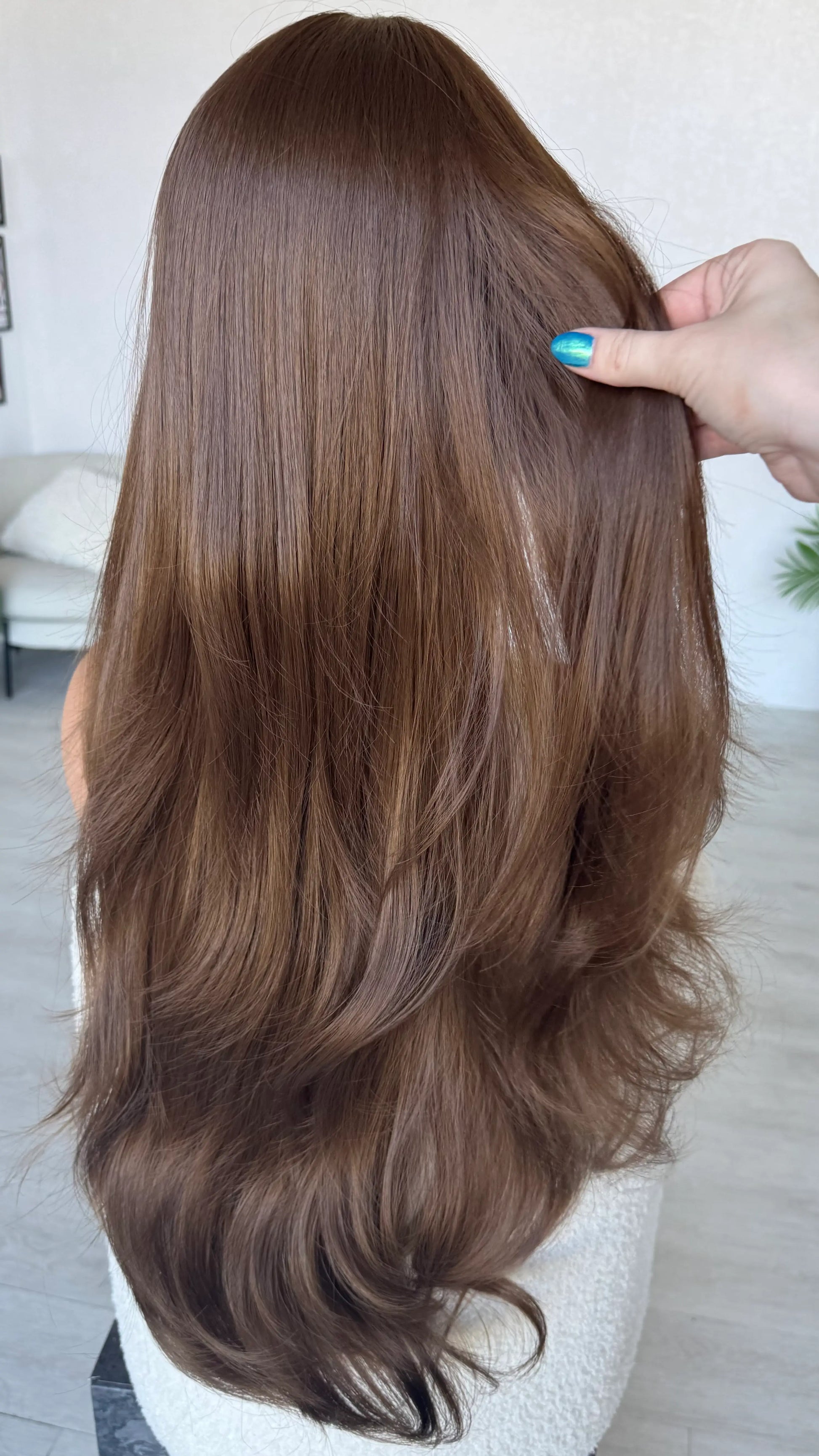 back view holding long brown hair light layers throughout.