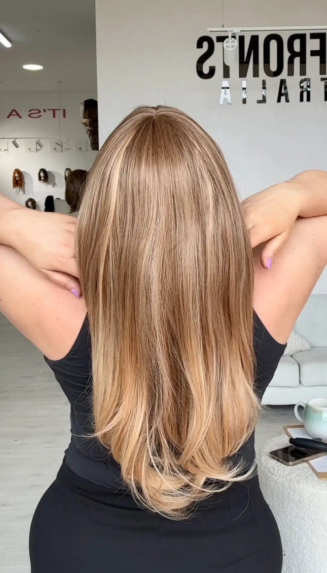 back view showing straight light golden brunette hair with middle part and fringe, heat safe hair with glueless cap for easy everyday wear.