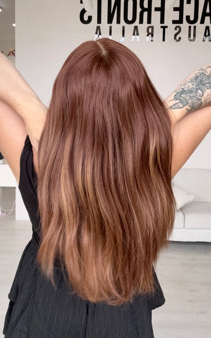synthetic heat safe wig from back view, holding long red copper hair that fades slightly on ends.