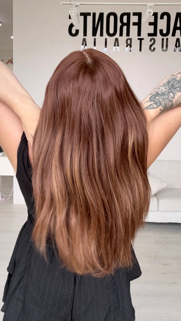 synthetic heat safe wig from back view, holding long red copper hair that fades slightly on ends.
