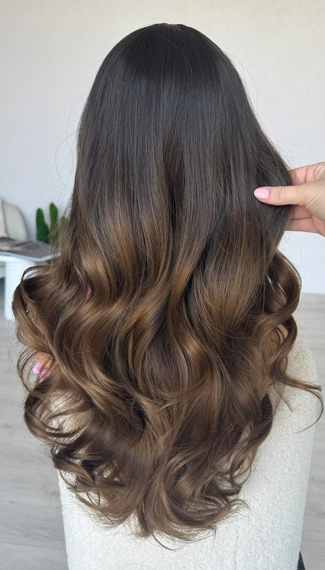 back view holding long wavy brunette hair, heat safe wig.