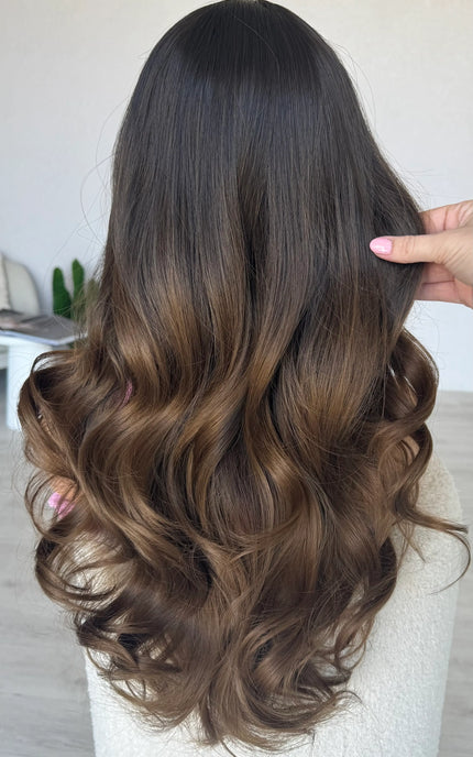 back view holding long wavy brunette hair, heat safe wig.