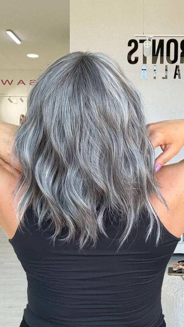 back view of wavy ash grey hair with soft platinum highlights, middle part with fringe.
