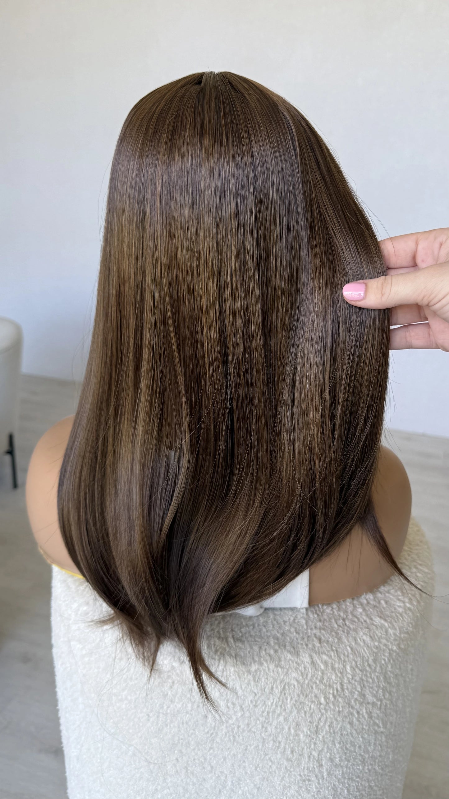 synthetic brunette topper from behind, holding the hair.