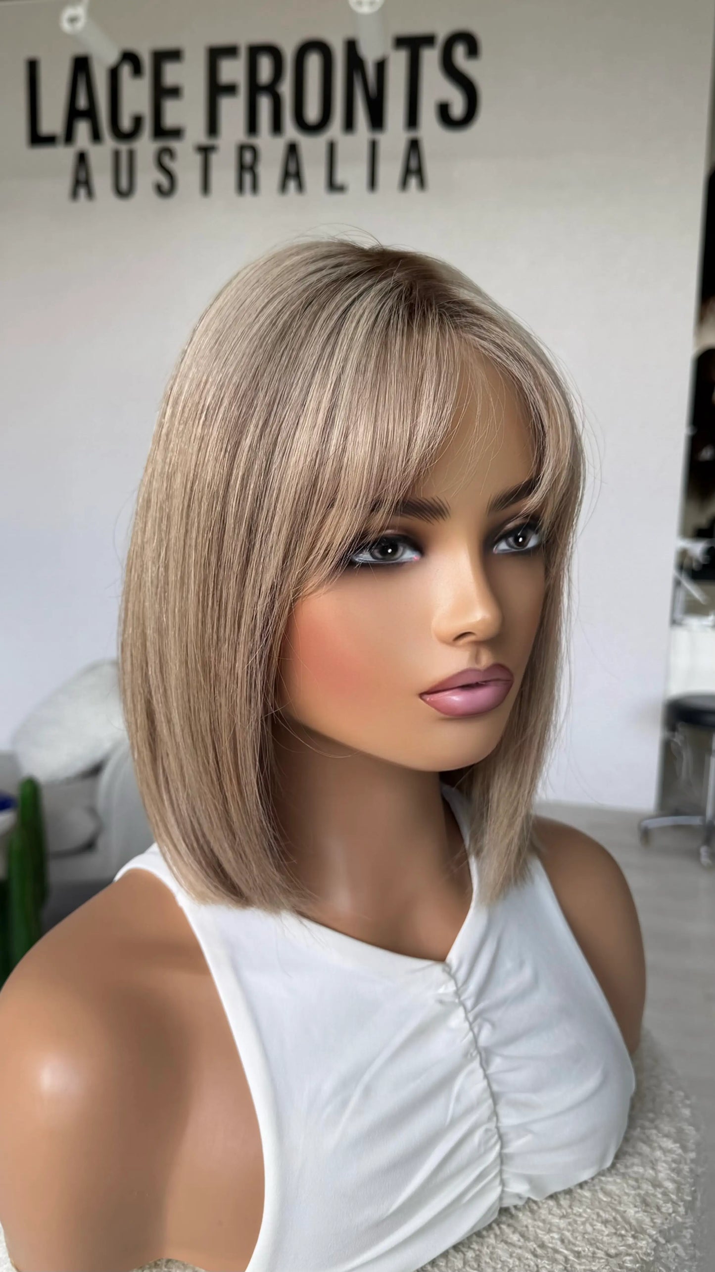 sandy beige blonde bob length hair, human hair lace front wig, side on view, fringe parted to the side.
