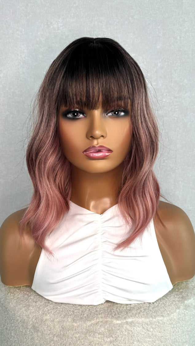 pink synthetic bob from the front on. dark root with bright pink wavy hair.