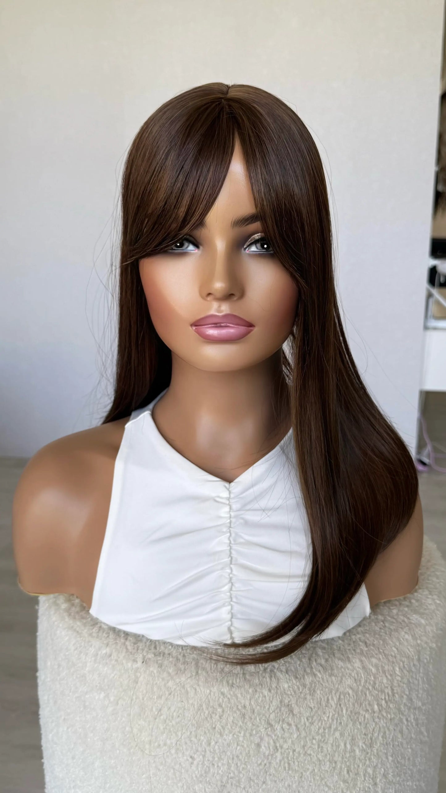 chestnut warm brunette topper middle part, fringe parted to the side.