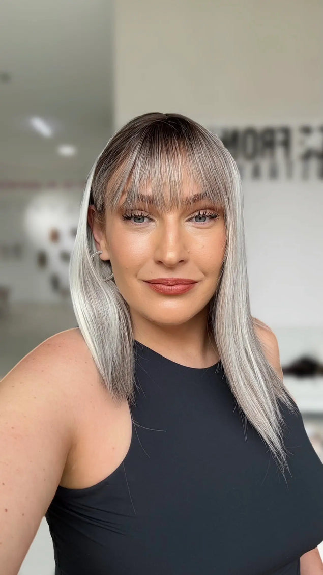 straight hair long bob with half hair tucked behind ear, wispy fringe with darker root to platinum highlights.