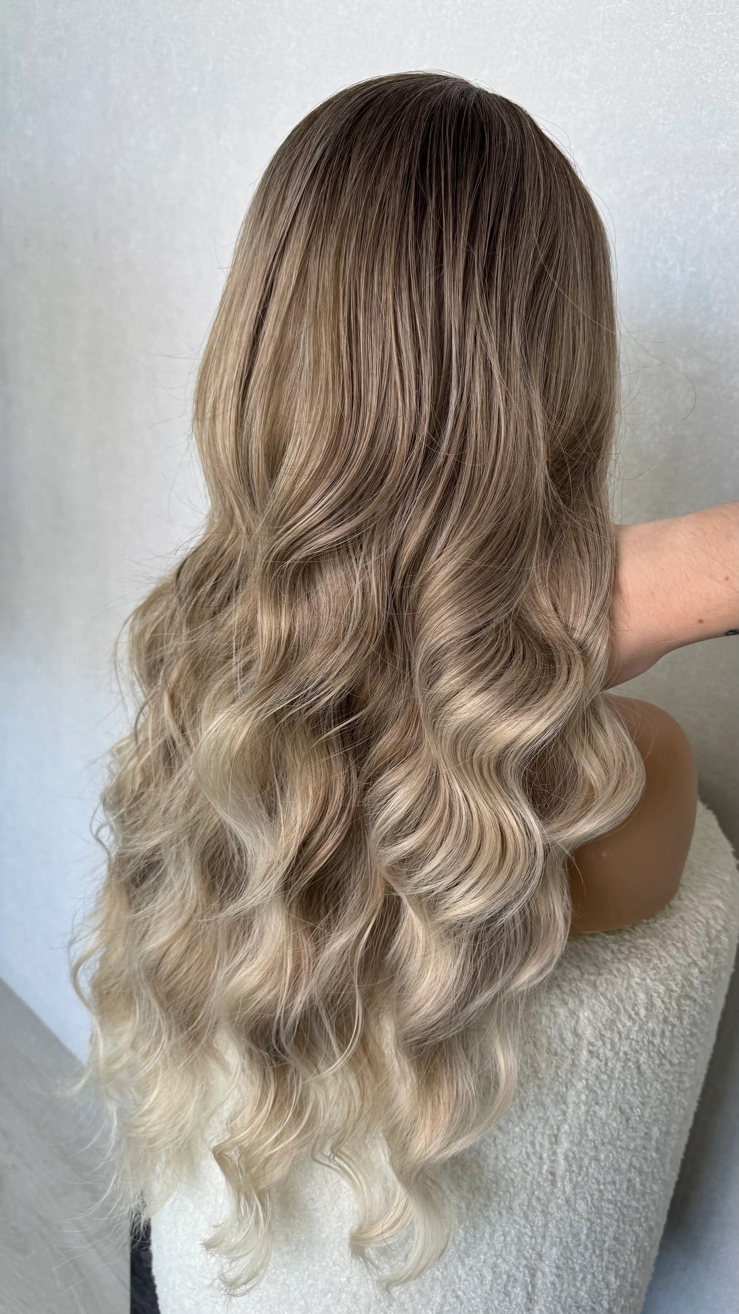 ash balayage synthetic wig, heat friendly. from the back view holding up hair to show natural colour. 