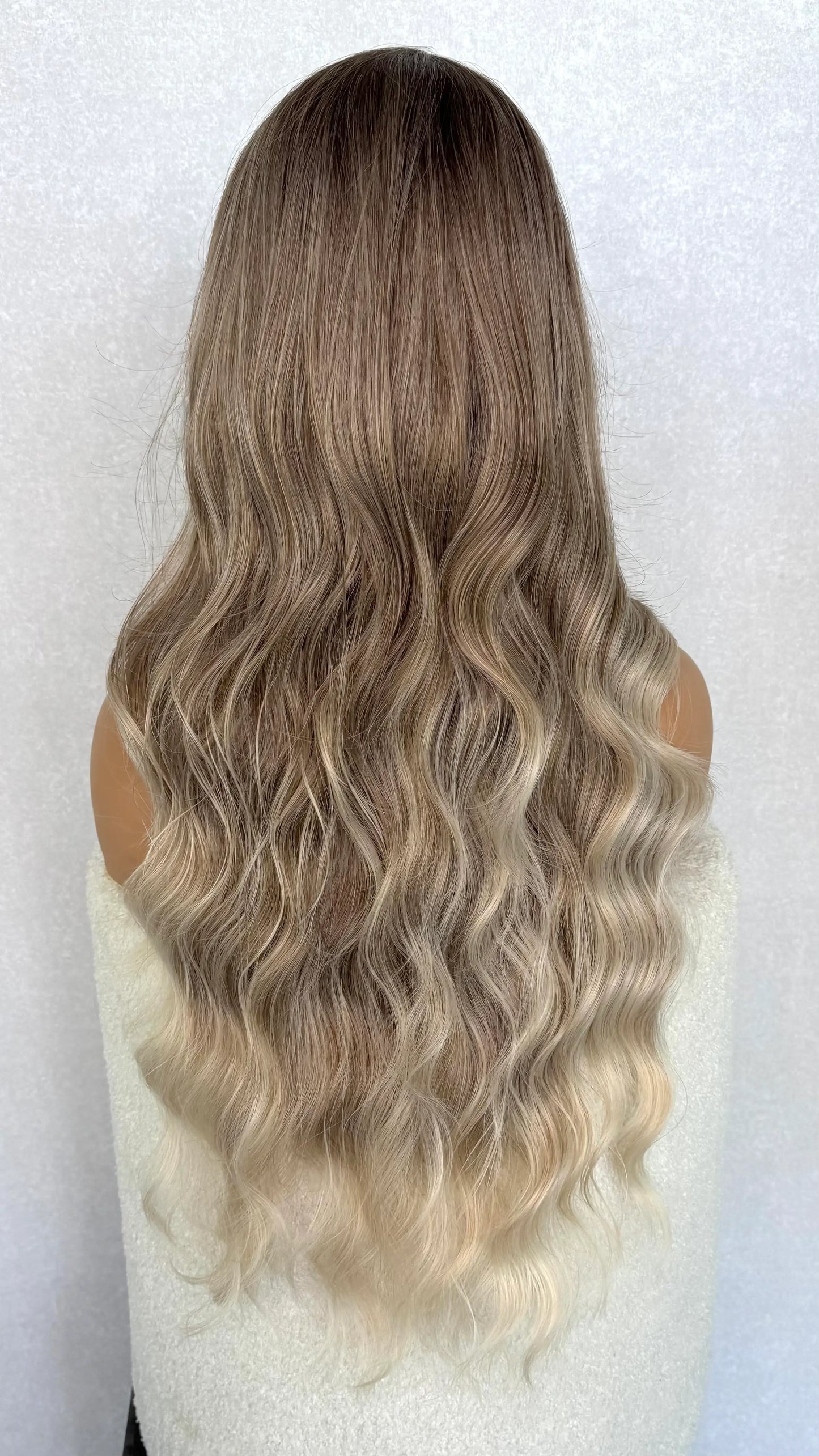 synthetic ash blonde wig from the back. long wig with waves. cool toned hair.