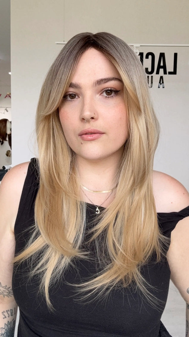 a vanilla blonde synthetic wig with a glueless cap and curtain bangs, middle part with long curtain bangs parted to the side. 