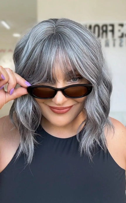 top view showing partline, middle part with soft natural fringe to eyebrow line. wavy heat safe hair with glueless wig cap for everyday easy wear.