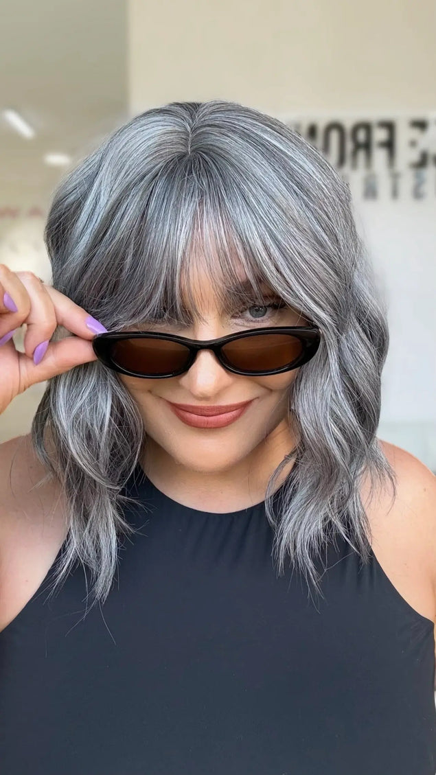 top view showing partline, middle part with soft natural fringe to eyebrow line. wavy heat safe hair with glueless wig cap for everyday easy wear.