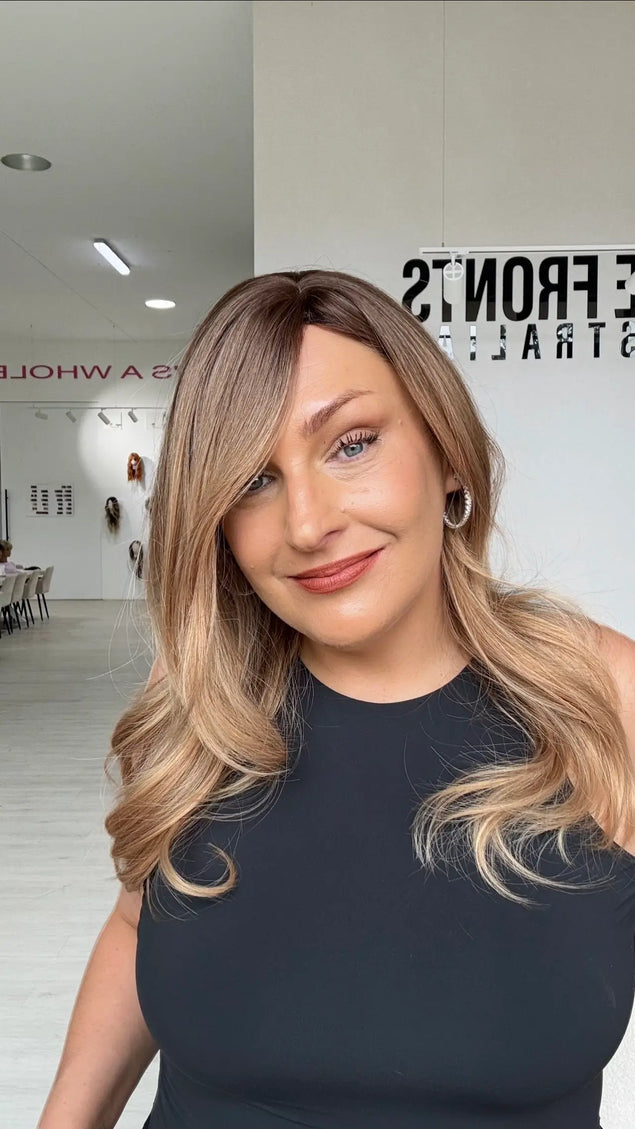 a soft golden brunette with light warm blonde ends, slight side part with long face framing layers. an elegant classy look.
