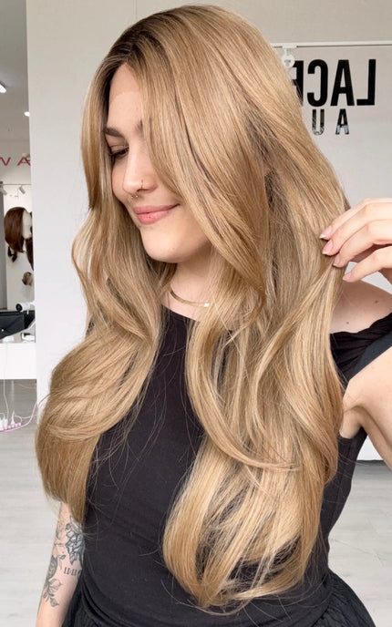 long length layered dark honey blonde hair, middle part with long curtain bangs, a glueless wig with adjustable straps and heat safe hair.