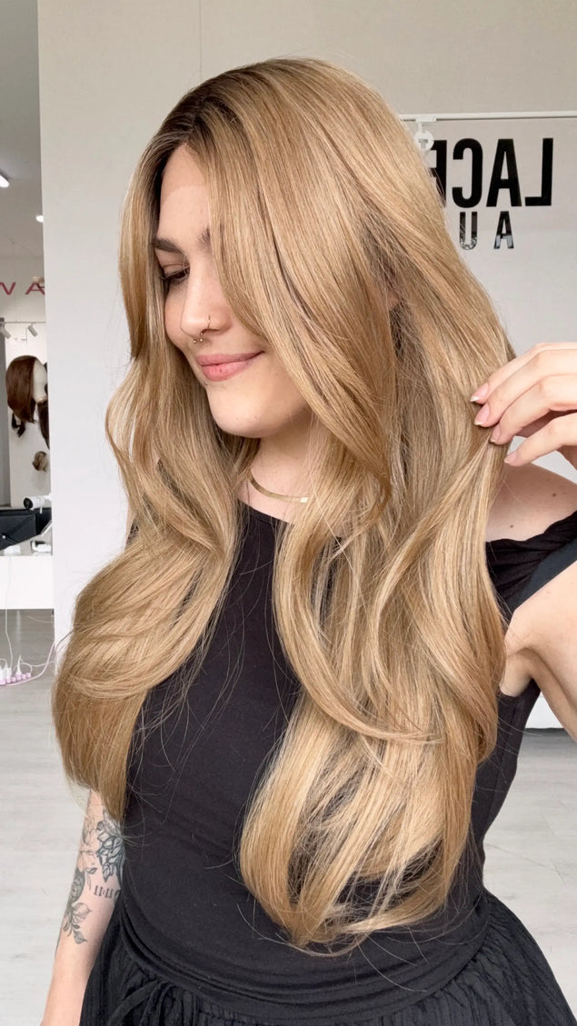 long length layered dark honey blonde hair, middle part with long curtain bangs, a glueless wig with adjustable straps and heat safe hair.