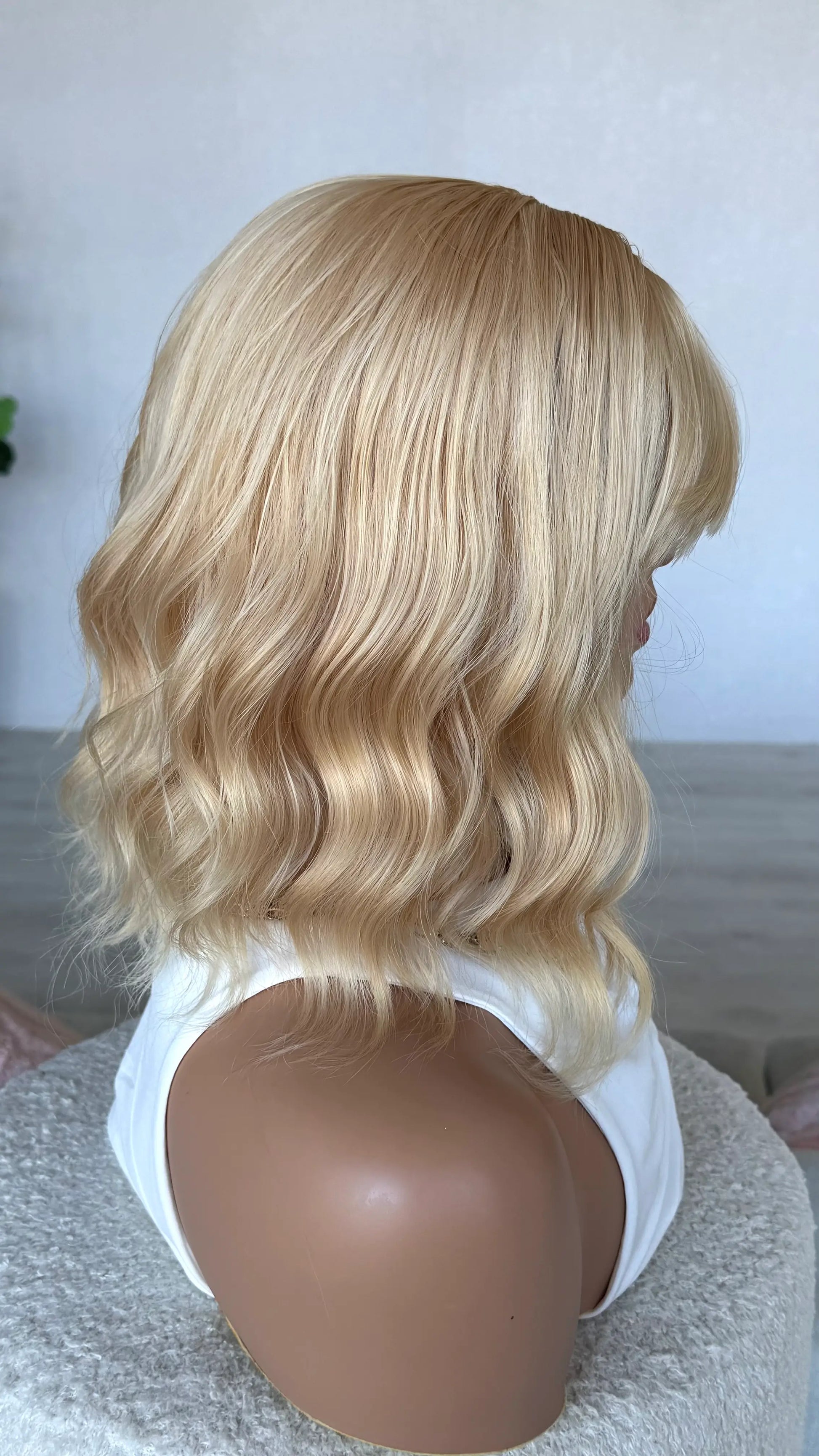 side on view of honey synthetic wig, heat safe hair, wavy blonde warm wig. 
