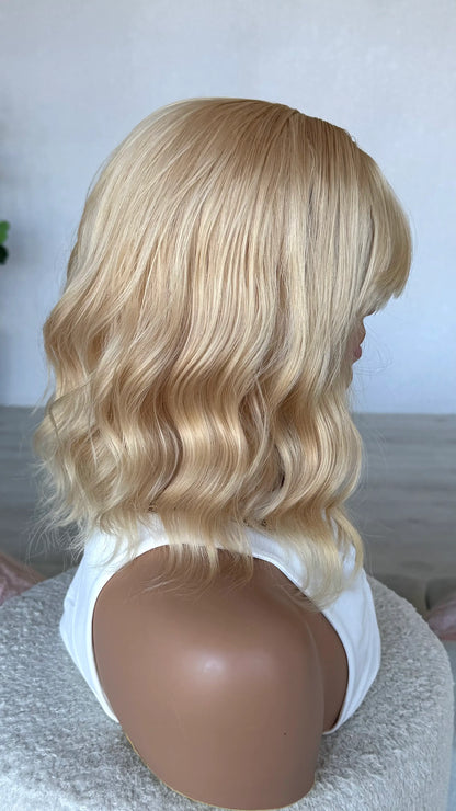 side on view of honey synthetic wig, heat safe hair, wavy blonde warm wig. 