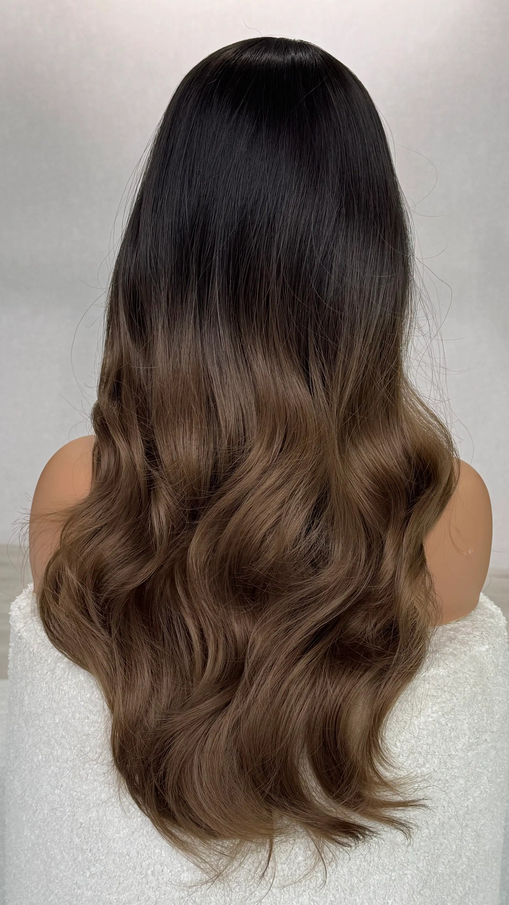 wig from the back view showing ombre brown hair, dark root to light end. wavy long wig. heat safe wig.