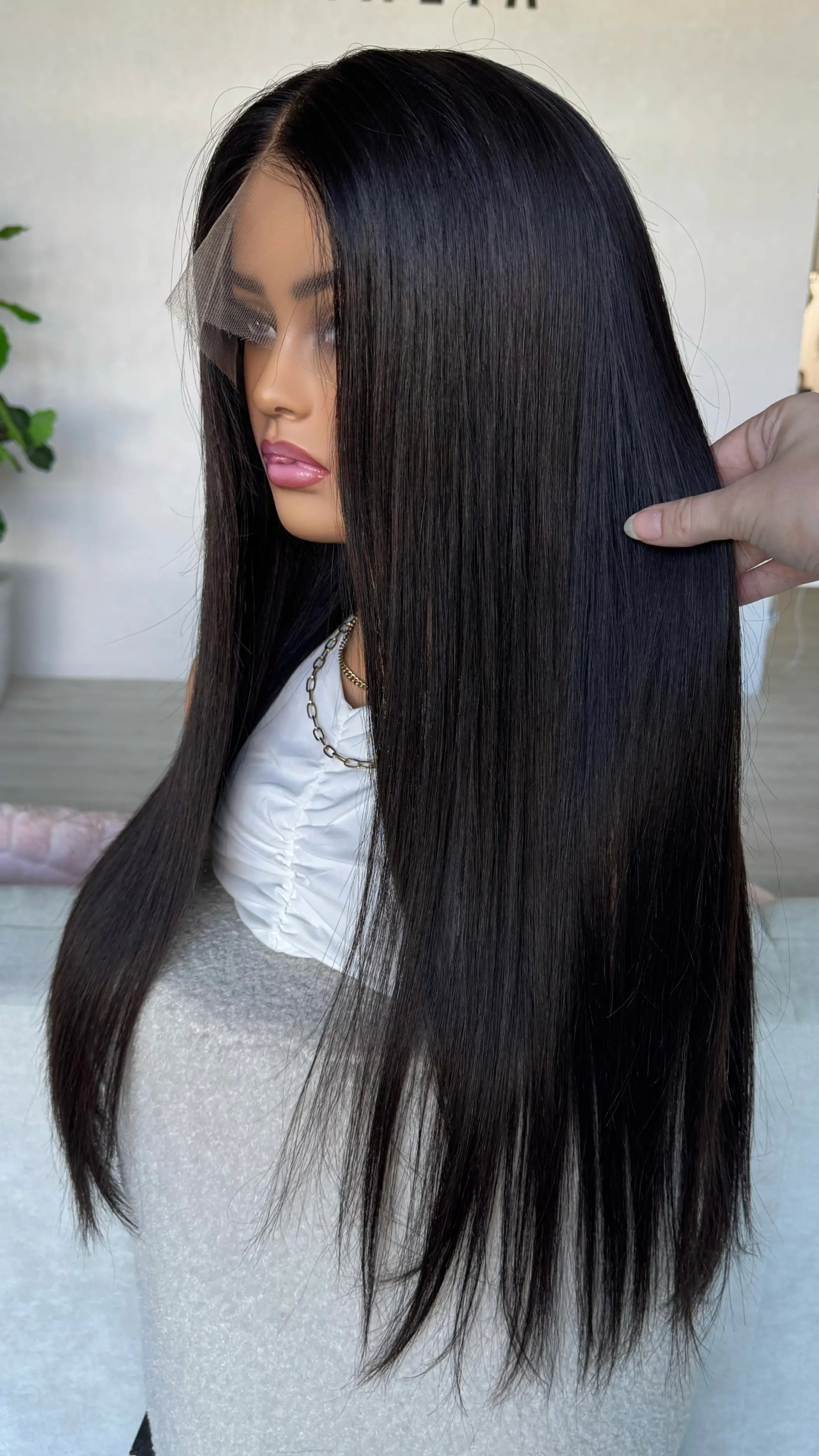 side on view holding the black hair wig. handmade wig in australia, natural hairline.