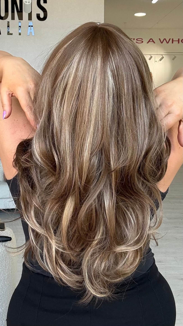 Medium length 20–22 inch warm brunette hair with ash and honey blonde highlights, cut in soft layers.