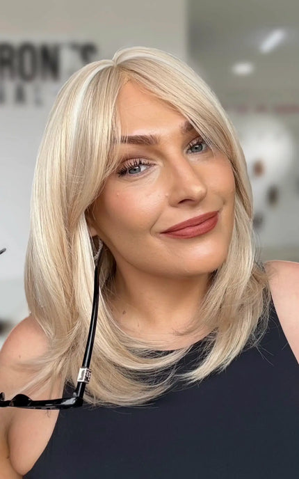 glueless light creamy blonde long bob length with layers throughout for movement, midde part with long curtain bangs.